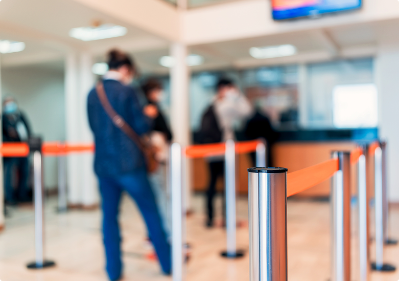 People standing in line inside a bank lobby, waiting to be served at the counter.