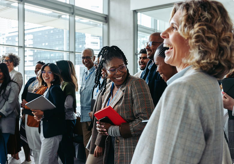 Diverse group of professionals laughing and engaging at a networking event in a modern office setting.