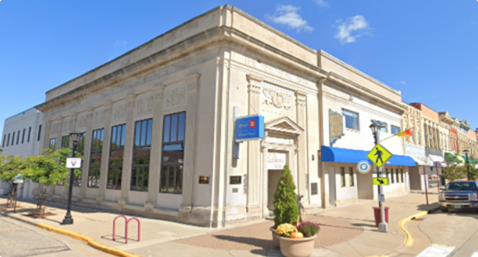 Historic BMO Harris Bank building located on a downtown corner with neoclassical architecture, arched windows, and a pedestrian crosswalk in front.