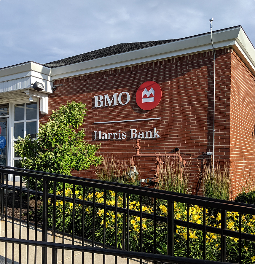 Exterior of a BMO Harris Bank retail branch with brick facade, flower landscaping, and visible signage—ideal example of a sale-leaseback property.