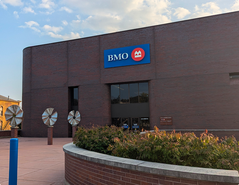 Modern curved BMO bank building with public plaza, brick exterior, and prominent signage—part of Brookline’s sale-leaseback property portfolio.